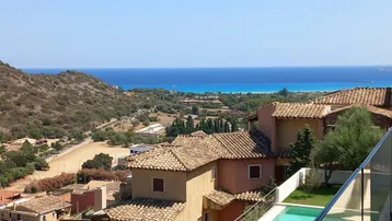 Panoramablick auf das Meer, die grüne Landschaft und die Dächer der Häuser mit einem kleinen Poolbereich.