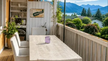 Heller Balkon mit Esstisch und Stühlen, bietet einen weiten Blick auf den See und die Berge.