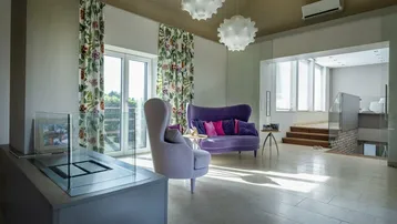 Helles Wohnzimmer mit farbenfrohen Möbeln, großen Fenstern und einem modernen Kamin.