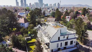 Luftaufnahme eines modernen Wohngebäudes mit Stadtblick und grüner Umgebung.