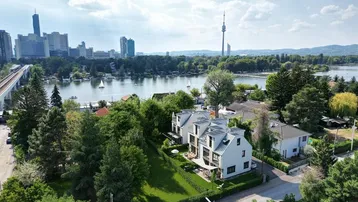 Luftaufnahme einer modernen Wohnanlage mit Blick auf die Stadt und einen See.