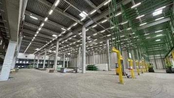 Geräumige Lagerhalle mit hoher Decke, Betonboden und industrieller Beleuchtung, bereit für die Nutzung.