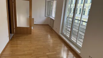 Helles Wohnzimmer mit Parkettboden, großen Fenstern und Zugang zu einem französischen Balkon.