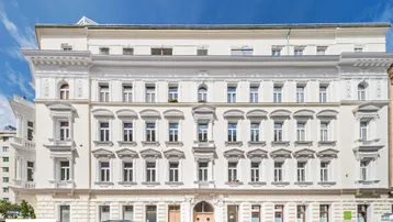 Klassisches Wiener Wohngebäude mit reich verzierter Fassade und vielen Fenstern unter blauem Himmel.