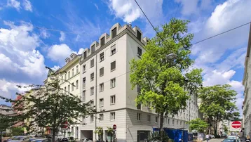 Mehrstöckiges Wohngebäude in städtischer Umgebung mit gepflegter Fassade und Bäumen.