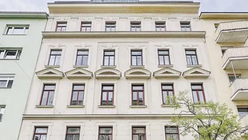 Klassische Fassade eines Mehrfamilienhauses mit modernen Akzenten im Dachbereich.