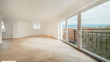 Heller Raum mit Fischgrätparkett, großen Fenstern und Zugang zu einem französischen Balkon mit Weitblick.