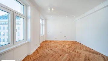 Helles Zimmer mit Fischgrätparkett und großen Fenstern, die einen Stadtblick bieten.