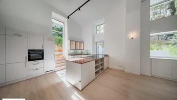 Moderne Küche mit hohen Decken, heller Holzboden und integrierten Geräten, bietet viel natürliches Licht.