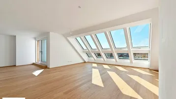 Helles Dachgeschosszimmer mit großen Dachfenstern, Holzboden und Zugang zu einem Balkon.
