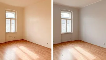 Helles, leeres Zimmer mit Parkettboden und einem Fenster, das Renovierungsbedarf aufweist.