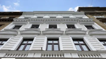 Klassische Altbaufassade mit vielen Fenstern und dekorativen Elementen von unten gesehen.