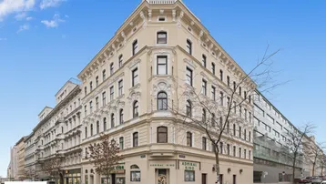 Großes Eckgebäude mit klassischer Architektur und vielen Fenstern in städtischer Umgebung.