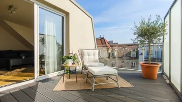 Geräumige Dachterrasse mit bequemen Gartenmöbeln und einem Olivenbaum, ideal zum Entspannen.