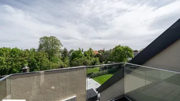 Moderne Dachterrasse mit Glasgeländer und weitem Blick ins Grüne, ideal zum Entspannen im Freien.