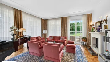 Elegantes Wohnzimmer mit Kamin, Flügel und Zugang zur Terrasse mit Gartenblick.
