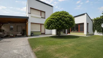 Modernes Einfamilienhaus mit gepflegtem Vorgarten, Rasenfläche und gepflasterter Auffahrt.