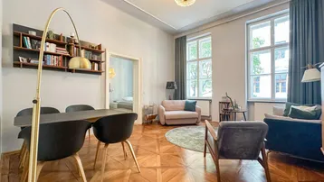Helles Wohn- und Esszimmer mit Fischgrätparkett, hohen Decken und großen Fenstern.