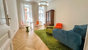Helles Wohnzimmer mit Fischgrätparkett, modernen Möbeln und zwei großen Fenstern.