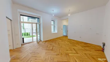 Heller Raum mit Fischgrätparkett und Zugang zu einem kleinen Gartenbereich, ideal für Wohn- oder Schlafzimmer.