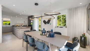 Eleganter Essbereich mit großem Tisch, modernen Pendelleuchten und Blick in den Garten.