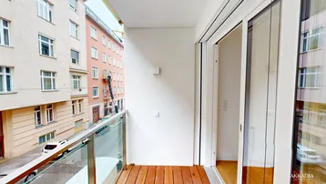 Moderner Balkon mit Holzfußboden und Glasgeländer, bietet einen Blick auf die belebte Stadtstraße.