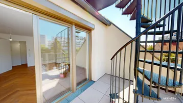 Geräumige Terrasse mit Wendeltreppe und Zugang zu einem hellen Innenraum mit Parkettboden.