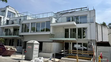 Modernes Neubaugebäude mit großen Fensterfronten und Balkonen in der Bauphase.