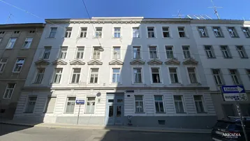 Klassische Fassade eines Mehrfamilienhauses mit vielen Fenstern und traditioneller Architektur an einer Straße.