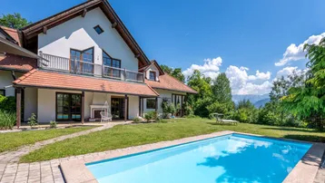 Großzügiger Gartenbereich mit Swimmingpool und Blick auf die umliegende Berglandschaft.