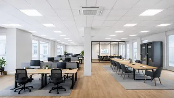 Modernes Großraumbüro mit hellen Arbeitsplätzen, einem Konferenzraum mit Glaswänden und großen Fenstern für viel Tageslicht.