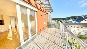 Geräumiger Balkon mit Fliesenboden, Glasüberdachung und weitem Blick ins Grüne.
