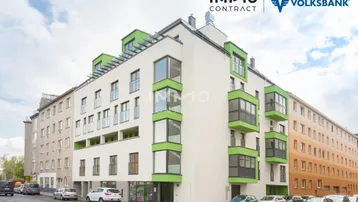 Modernes Mehrfamilienhaus mit weißer Fassade, grünen Akzenten und großen Fenstern in städtischer Umgebung.