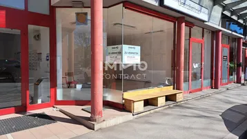 Schaufensterfront eines Geschäfts mit großen Glasfenstern und roten Rahmen, bereit zur Vermietung.