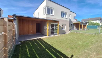 Rückseite eines modernen Reihenhauses mit überdachter Terrasse und Gartenbereich.
