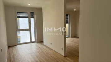 Helles, leeres Wohnzimmer mit Parkettboden und großen Fenstern, bereit zum Einzug.