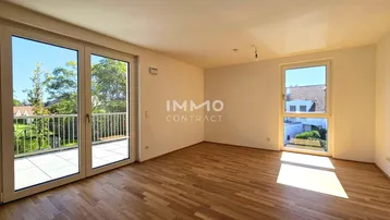 Helles Wohnzimmer mit Parkettboden und Zugang zu einer großen Terrasse, durchflutet von Tageslicht.