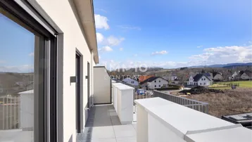 Geräumiger Balkon mit moderner Brüstung und weitem Blick über die umliegende Landschaft.