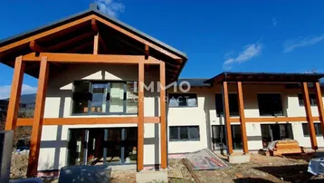 Neubau eines modernen Hauses mit Holzkonstruktion und großen Fenstern unter blauem Himmel.