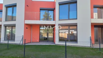 Moderne Reihenhäuser mit farbigen Akzenten, großen Fenstern und kleinen Gärten.