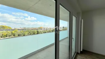 Heller Innenraum mit großen Schiebetüren, die zu einem Balkon mit Weitblick führen.