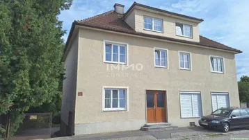 Klassisches Wohnhaus mit mehreren Fenstern und einem gepflegten Vorgartenbereich.