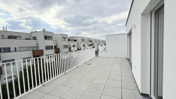 Geräumige Dachterrasse mit Fliesenboden und Blick auf die umliegenden Gebäude.