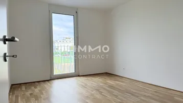 Helles Schlafzimmer mit Parkettboden und Fenster mit französischem Balkon.
