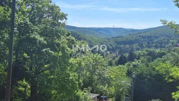 Weitläufiger Blick über bewaldete Hügel und Täler unter blauem Himmel.