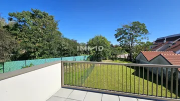 Geräumige Terrasse mit Fliesenboden und weitem Blick ins Grüne sowie auf die umliegenden Häuser.