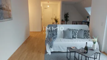 Helles Wohnzimmer mit Parkettboden, Sofa und offenem Übergang zum Eingangsbereich.