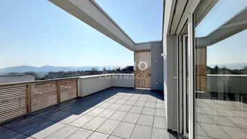 Geräumige Dachterrasse mit modernen Fliesen, Holzgeländer und weitem Blick in die Landschaft.