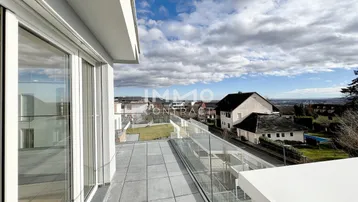 Moderne Terrasse mit Glasgeländer und weitem Blick über die umliegende Landschaft.