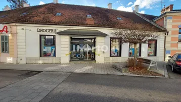 Gebäudeansicht einer Drogerie mit Schaufenstern und Eingangsbereich an einem sonnigen Tag.